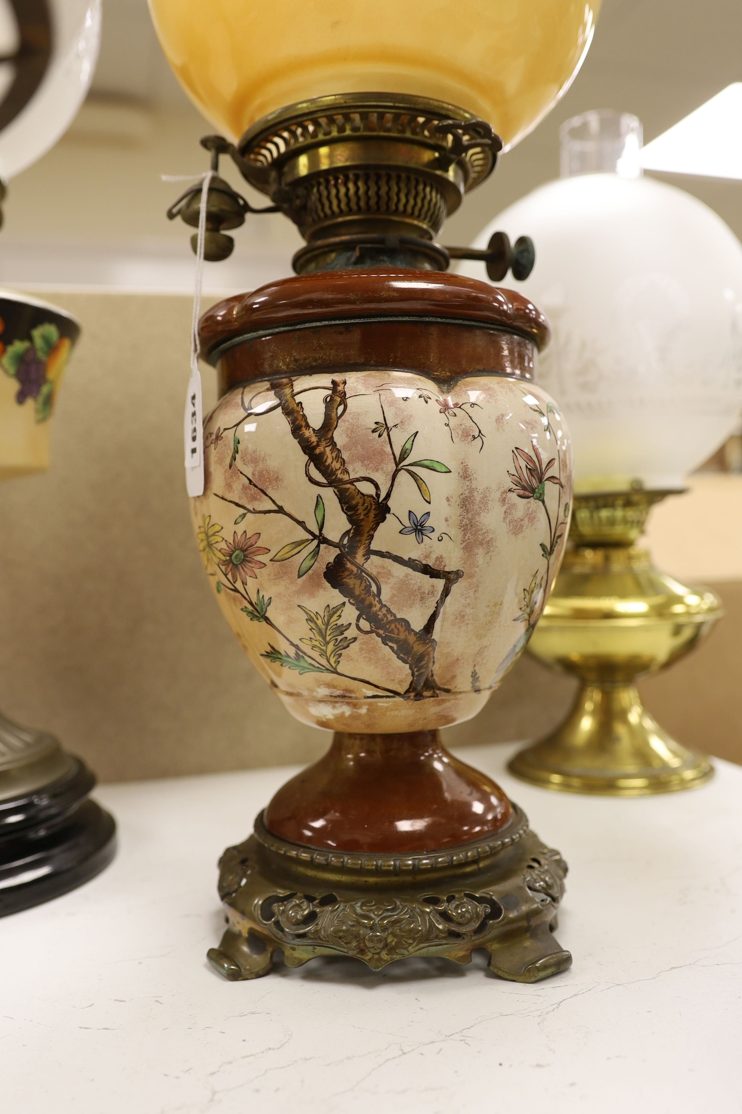 A Doulton style pottery oil lamp and four other glass and brass oil lamps, tallest 54 cms including glass shade.